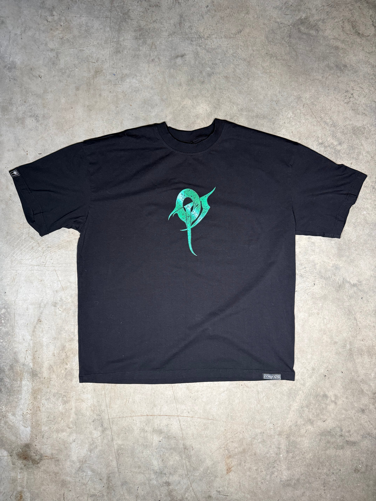 OverPower Strength Wear black oversized tee laid flat, front view with the green OP monogram